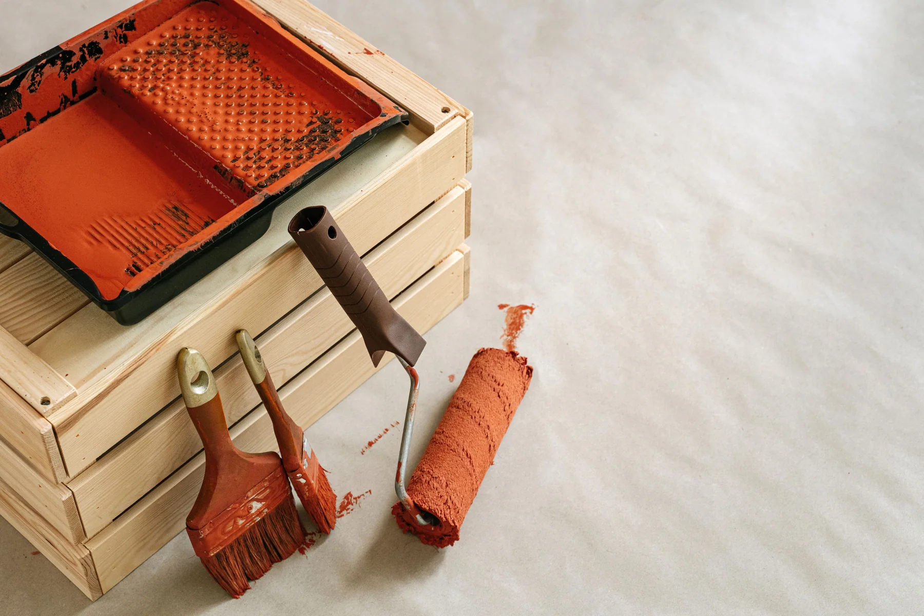 Paint brushes, roller and tray arranged for a painting project